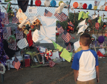 A young visitor contemplates the memorial and the prayer flags.