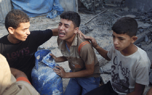 Palestinian relatives mourn for victims of the Duheir family, near the rubble of their home, after it was destroyed by an Israeli air strike in Rafah on July 29, 2014, in the southern of Gaza strip.