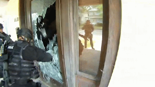 Glass shatters as SWAT uses a battering ram against an unlocked storm door.