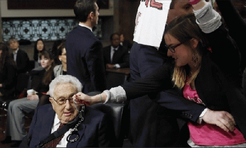 Alli McCracken, Co-director of the peace group CODEPINK, dangles a pair of handcuffs in front of former Secretary of State Henry during a protest at a Senate hearing in January 2015.