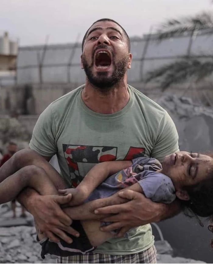 A Gazan father holds his daughter, murdered by Israeli colonial forces, as he carries her out of the rubble of a building. October 9, 2023